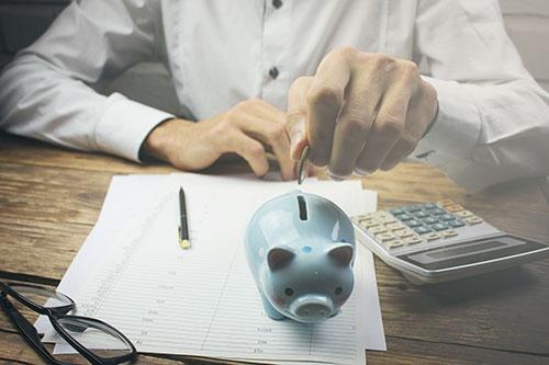 Man Putting Change in Piggy Bank